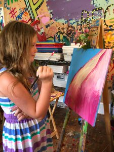 a girl painting on canvas in a room