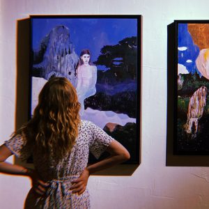 a woman looking at a painting on a wall