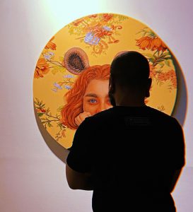 a man looking at a painting on a wall
