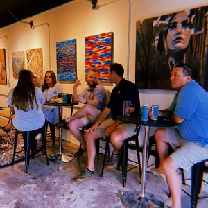 a group of people sitting at tables in a room with paintings on the wall
