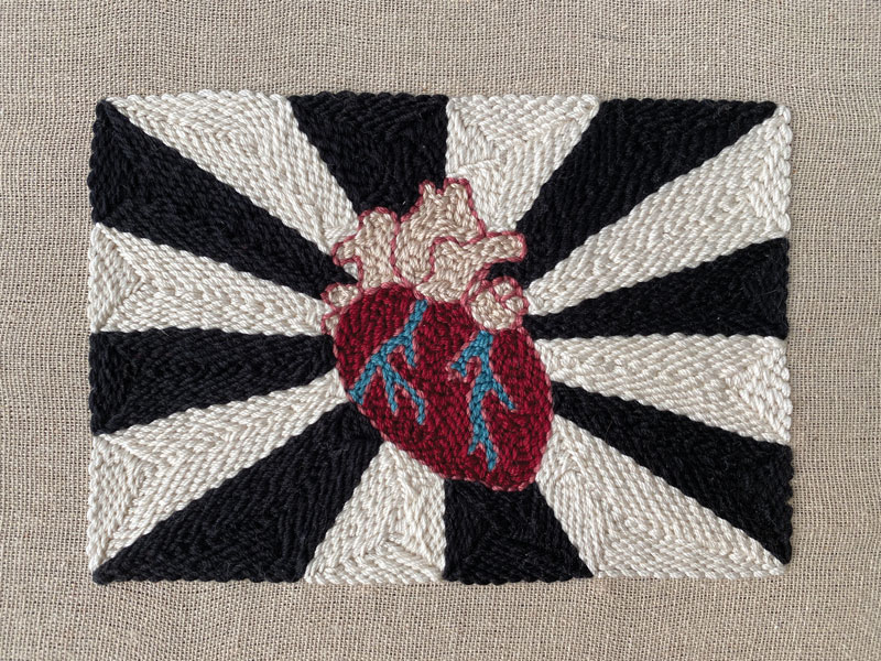 a black and white and red heart with blue and red threads