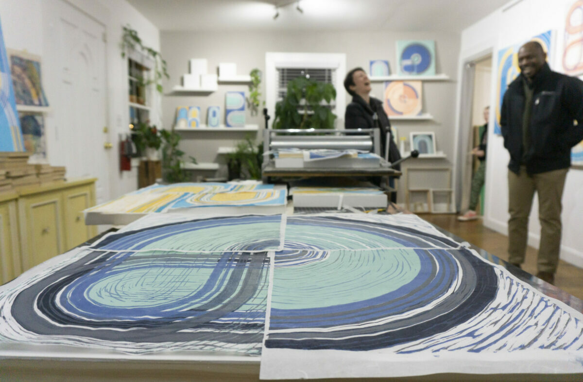 a group of people in a room with art prints