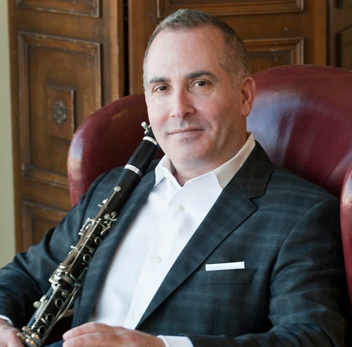 a man sitting in a chair holding a clarinet