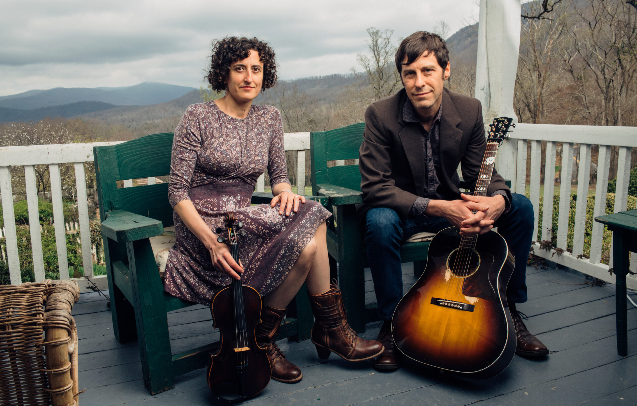 a man and woman sitting on a bench with musical instruments