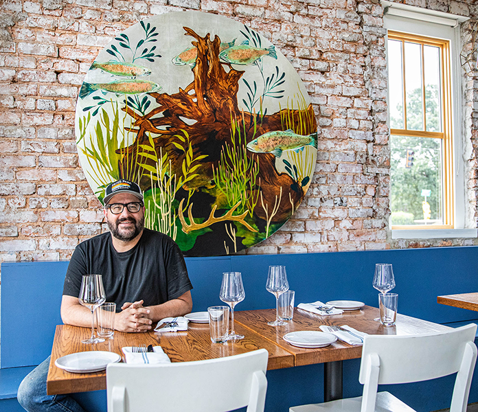 a man sitting at a table with glasses and a painting on the wall
