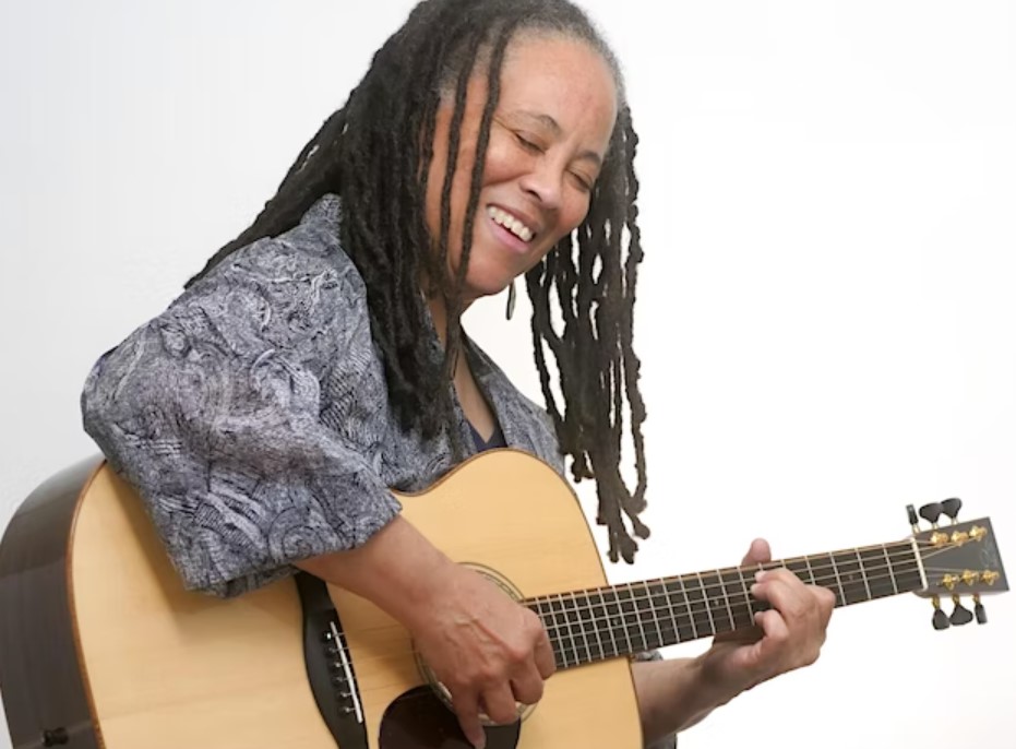 a woman with dreadlocks playing a guitar
