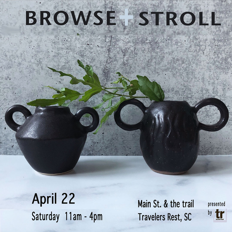 a couple of black vases with handles and a plant in them