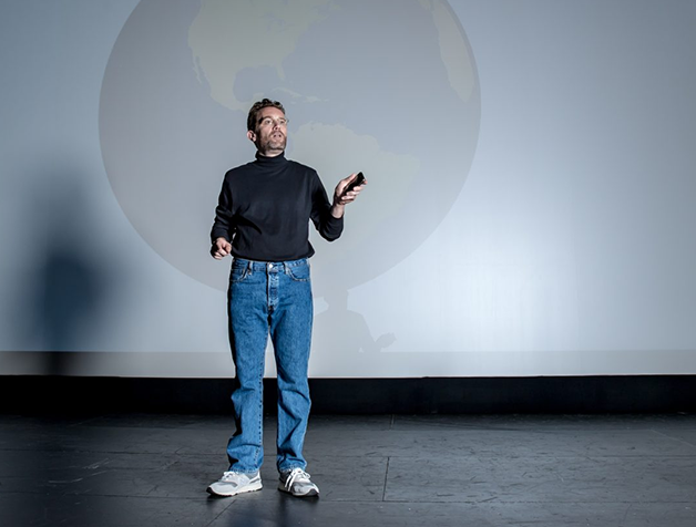 a man standing on a stage holding a remote