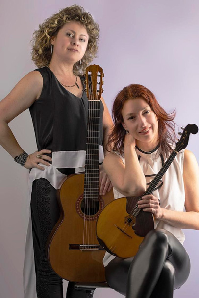 two women posing with guitars