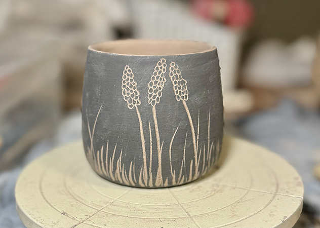 a grey and white ceramic cup with flowers on it