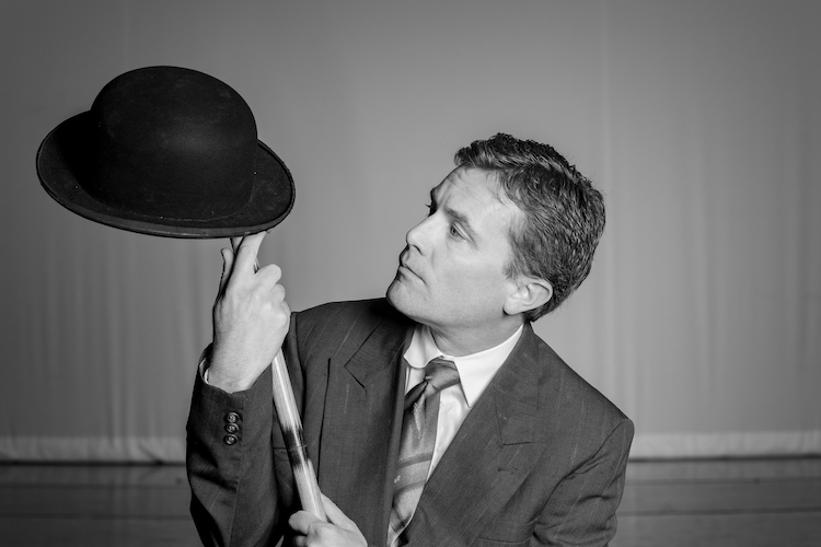 a man in a suit holding a hat and bat
