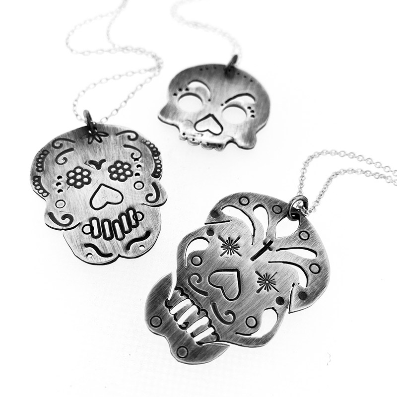 a group of silver skulls necklaces