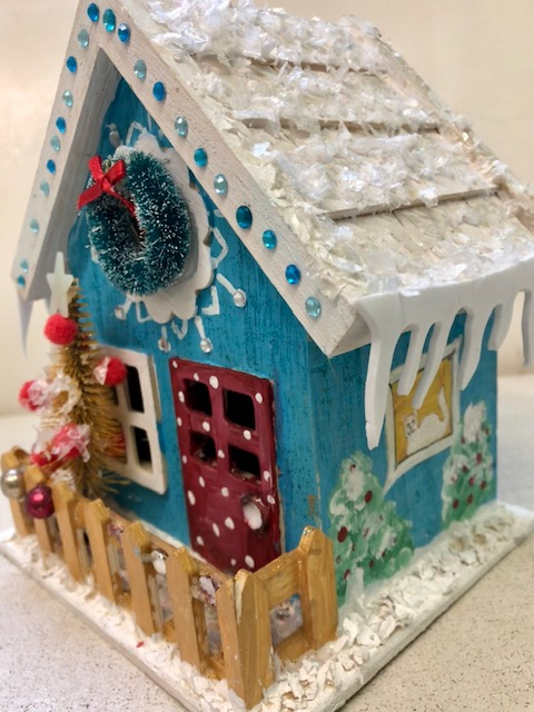 a small blue house with a white roof and a wreath