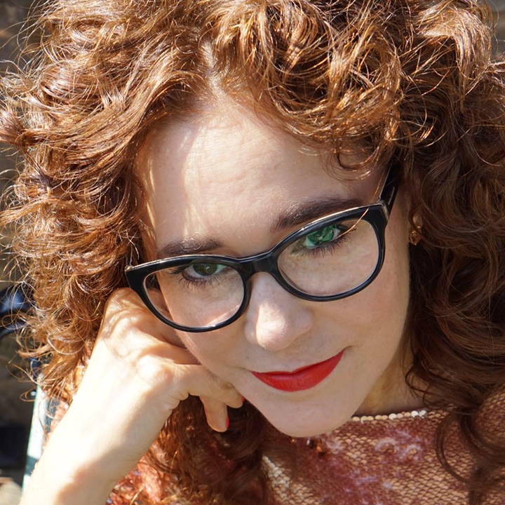 a woman with curly red hair wearing glasses
