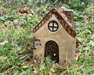 a small ceramic house in the grass