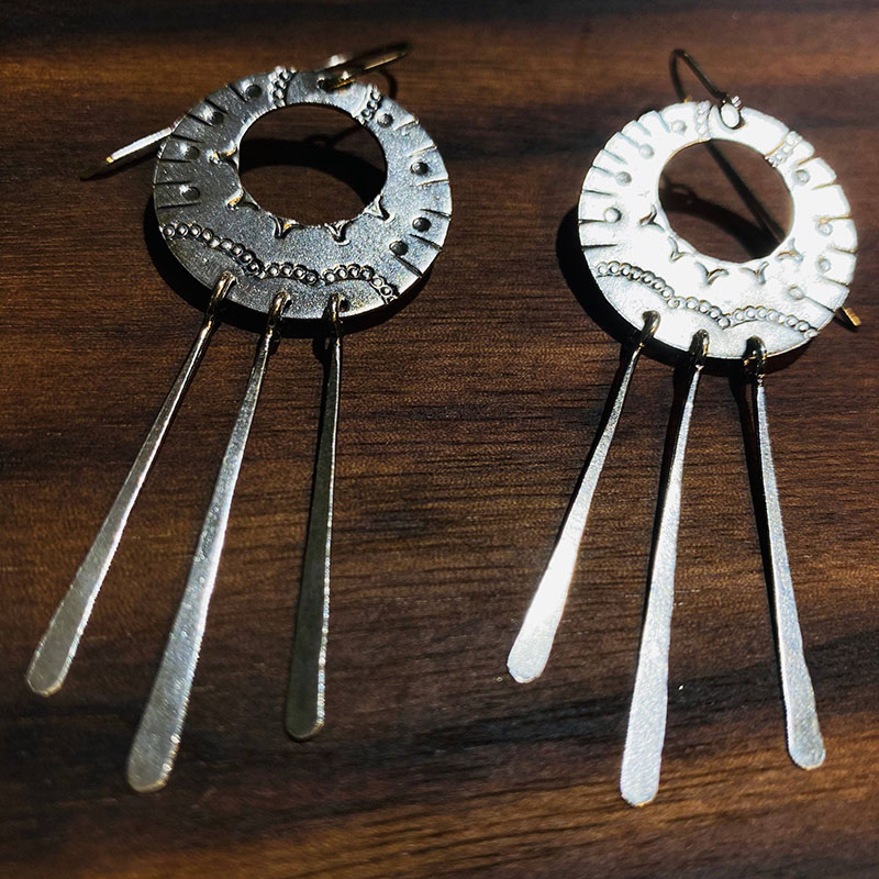 a pair of earrings on a wood surface