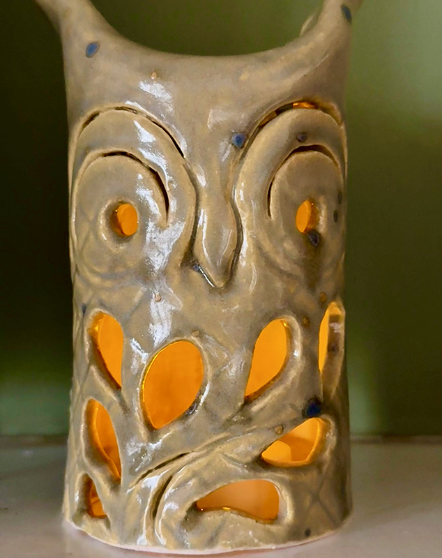 a ceramic candle holder with a face carved out of it