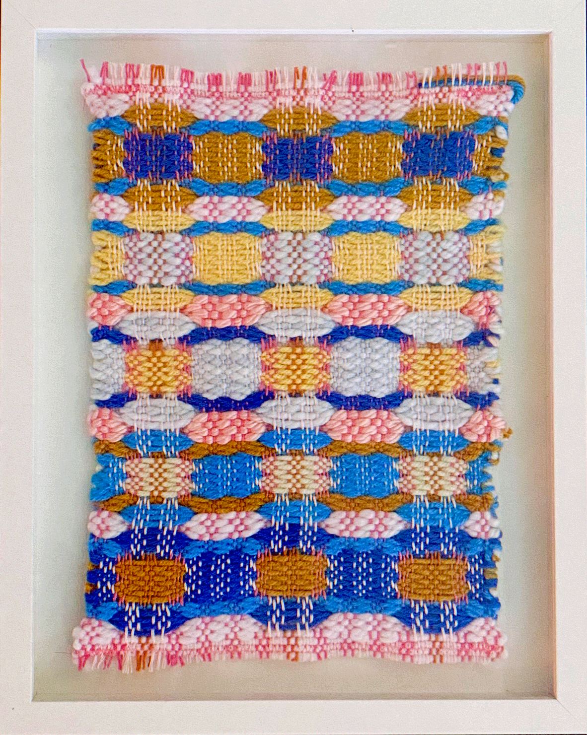a colorful woven fabric in a white frame