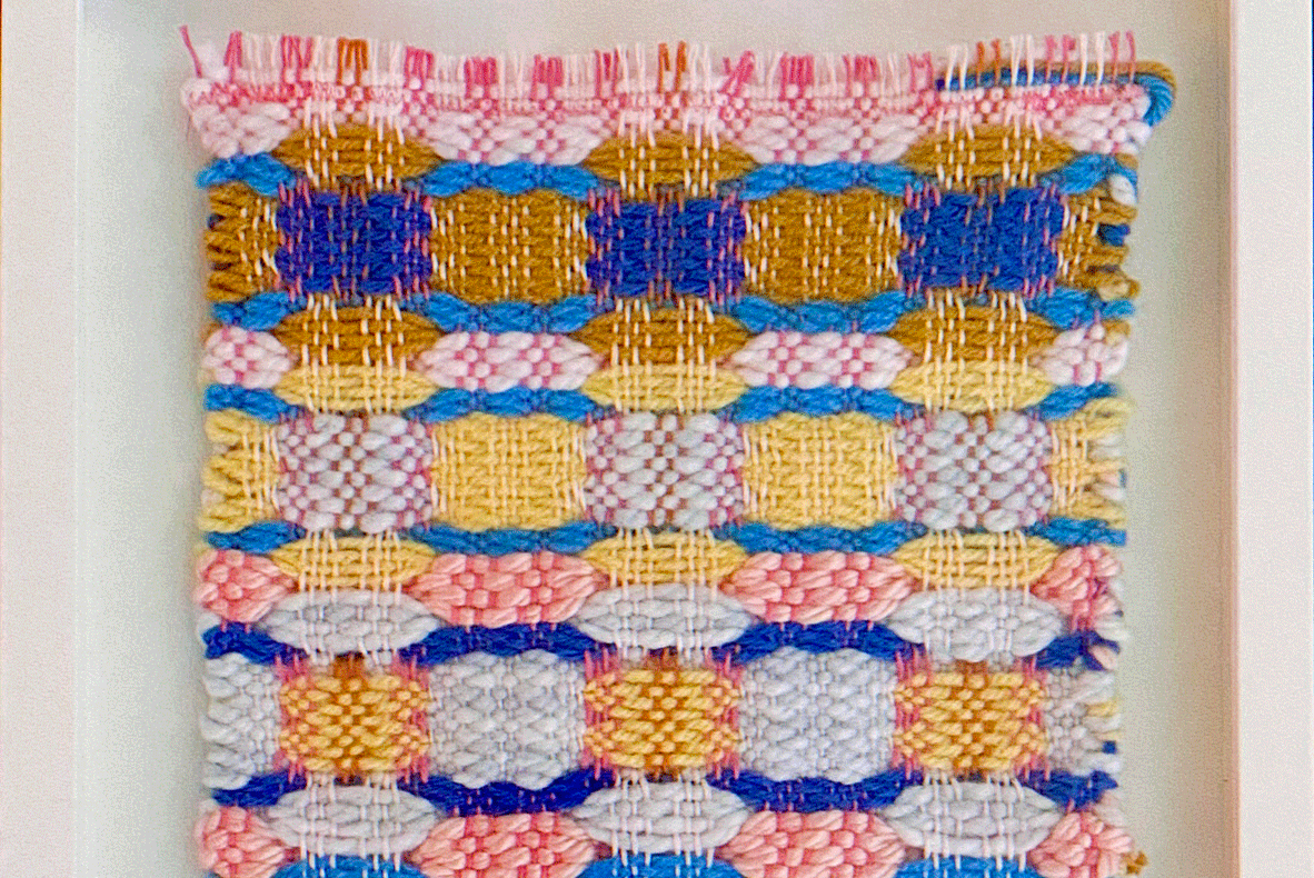 a colorful woven fabric in a white frame