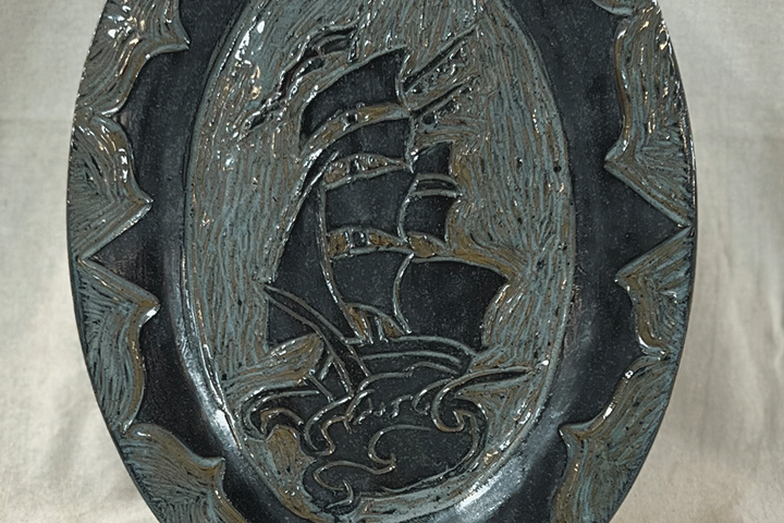 a decorative oval plate with a ship on it