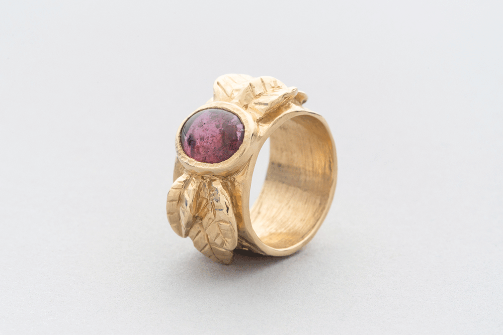 a gold ring with a red stone