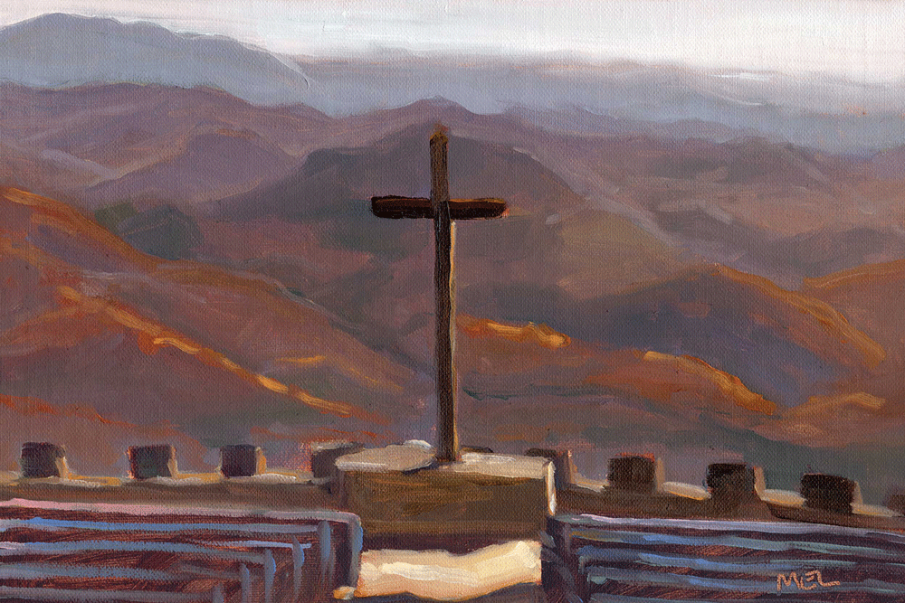 a cross on a platform in front of a mountain range