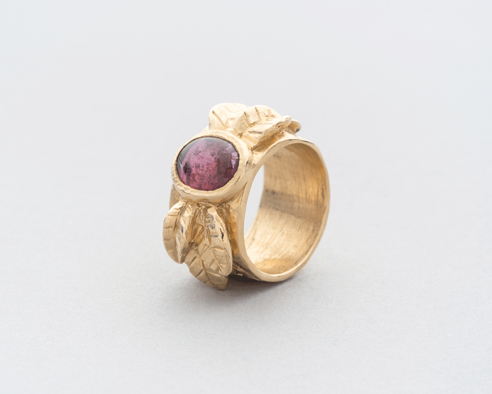 a gold ring with a red stone