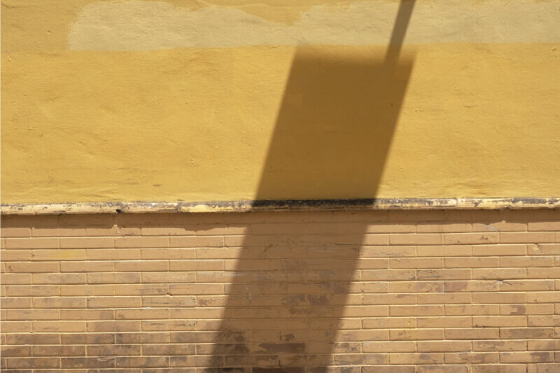 a shadow of a pole on a wall