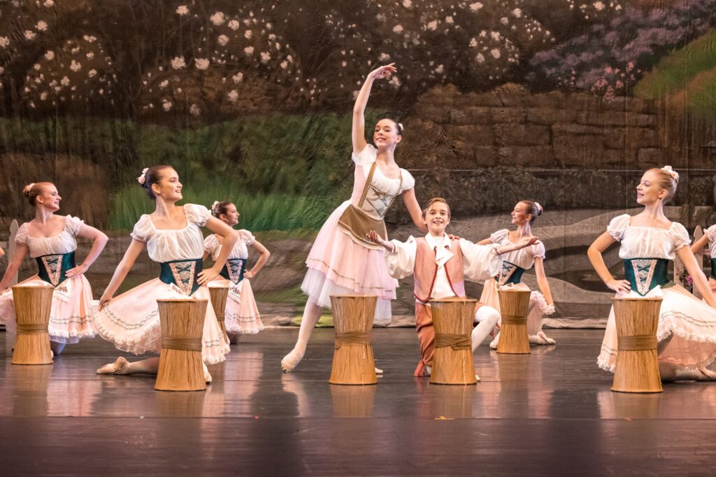 Ballet performance with dancers and props.