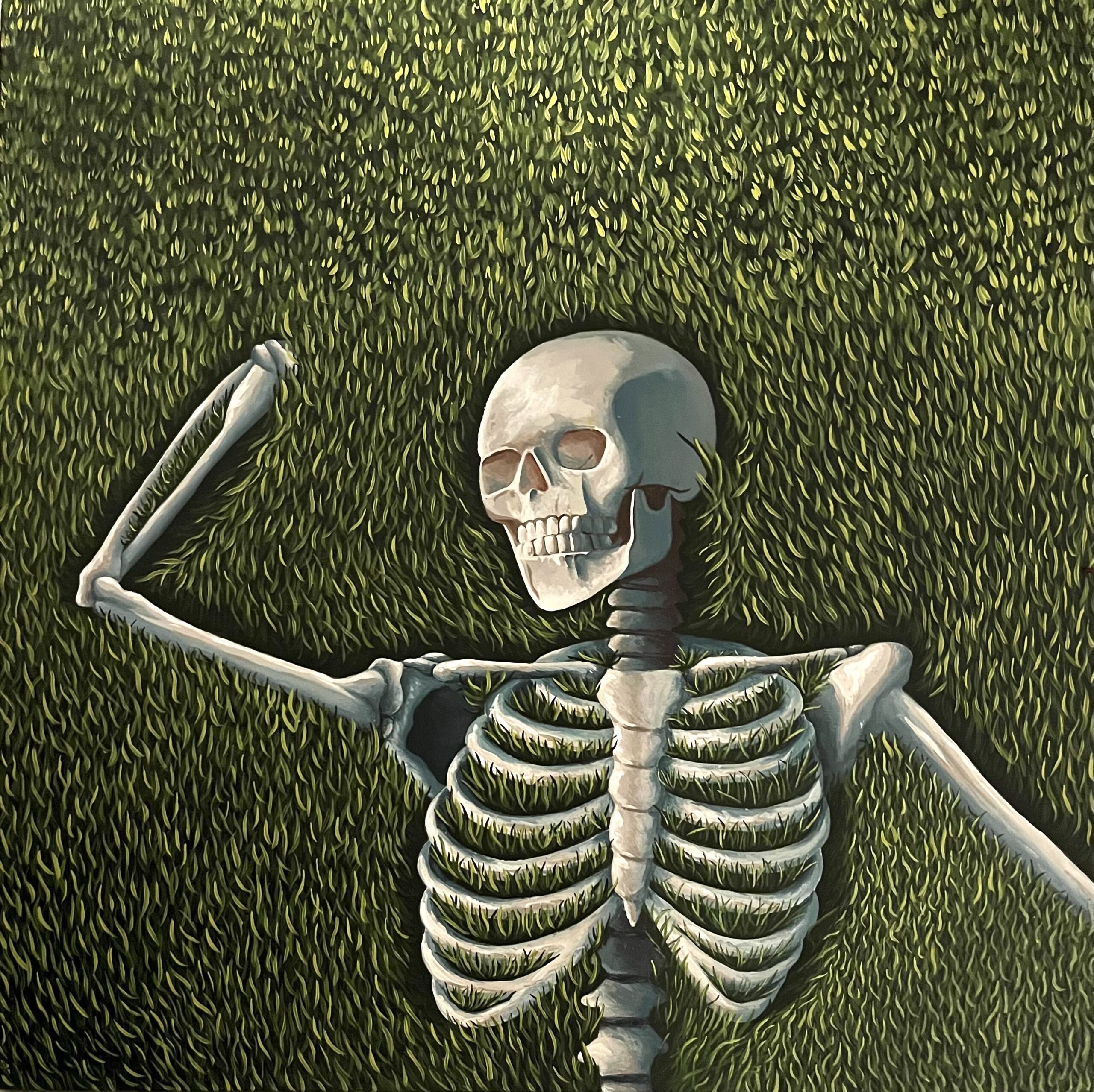 Skeleton lying on green grass.