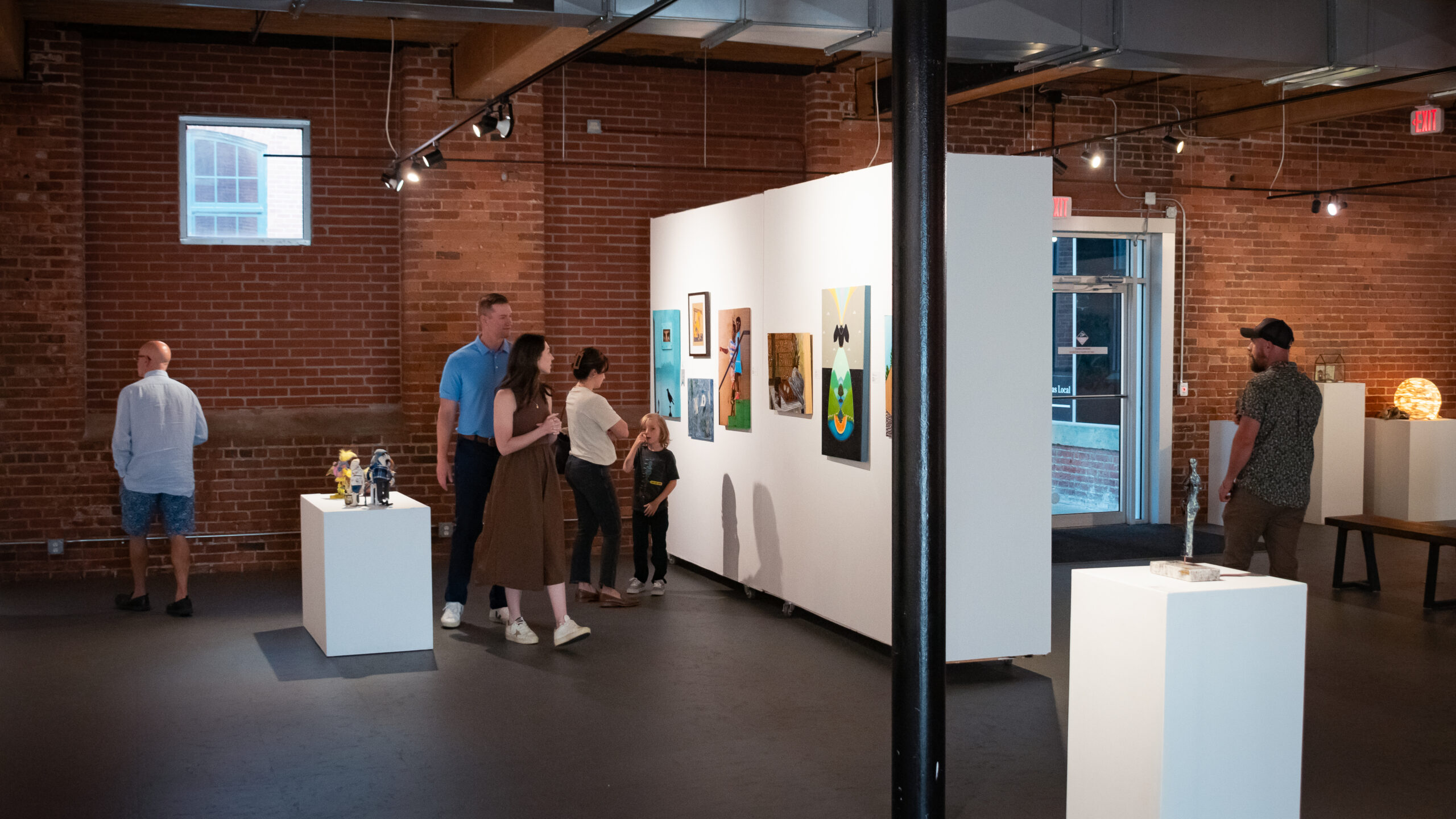 Art gallery with visitors exploring exhibits.