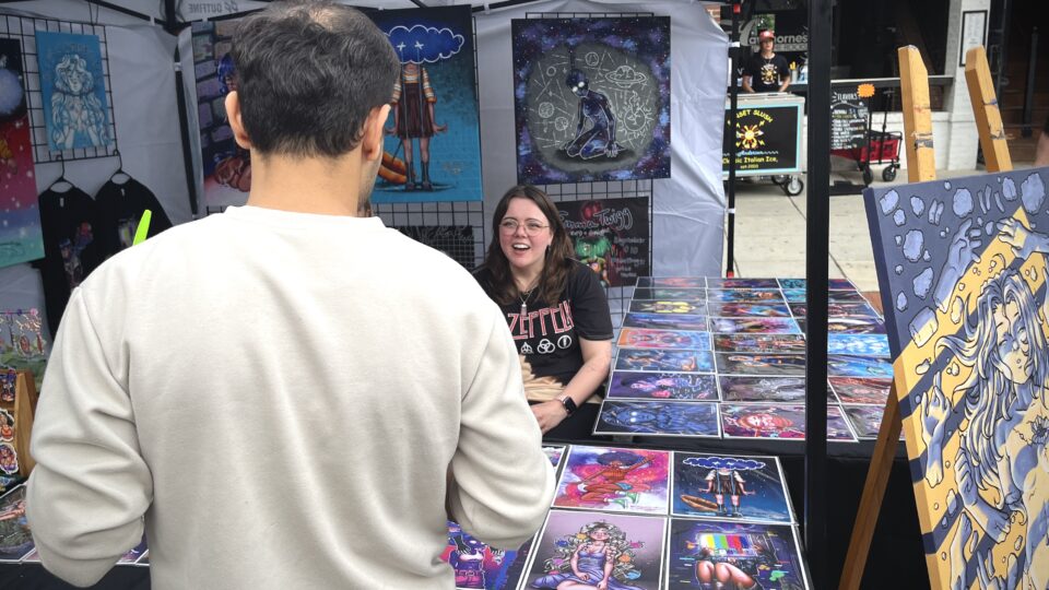 Art vendor at outdoor market.