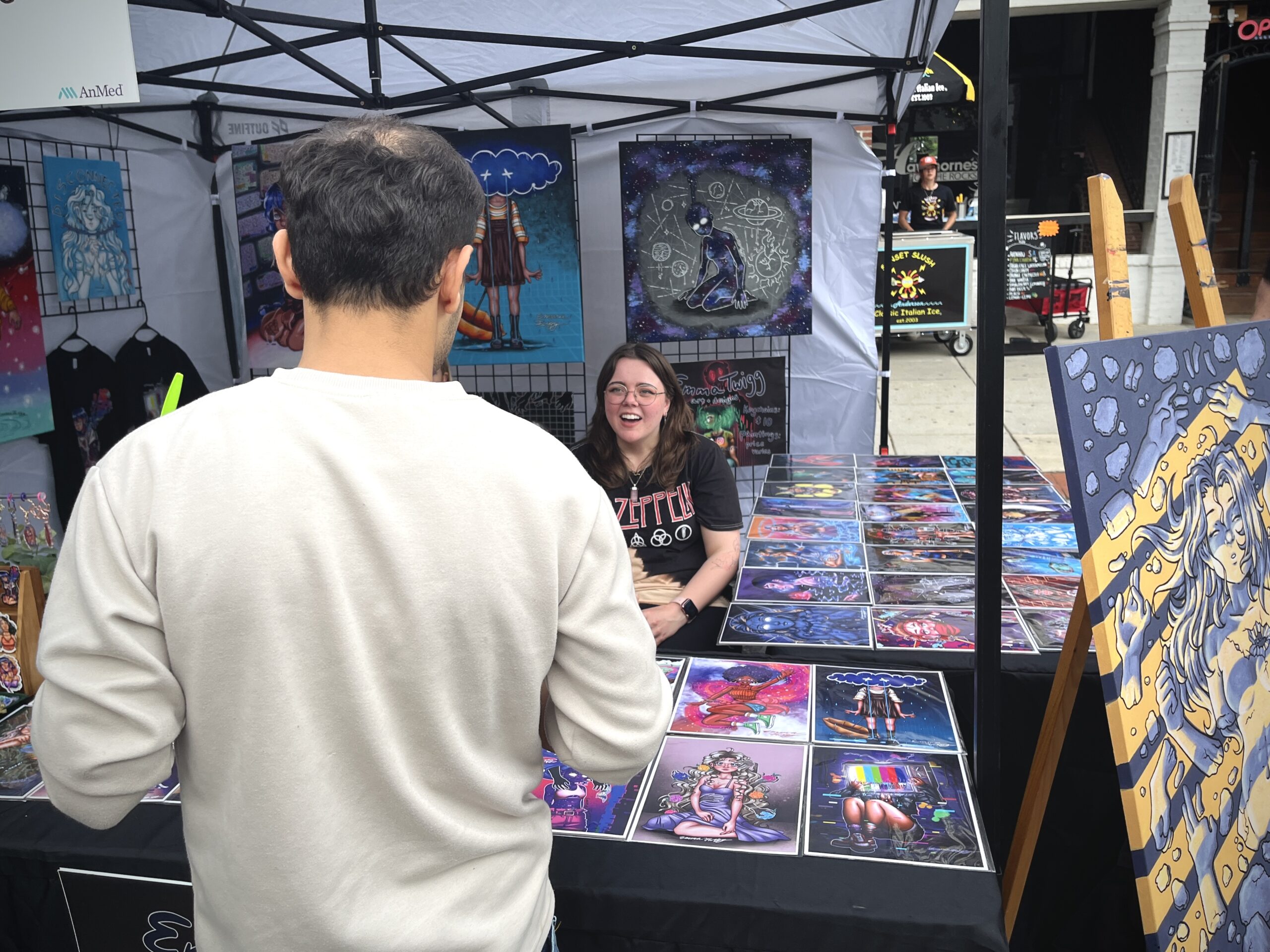 Art vendor at outdoor market.