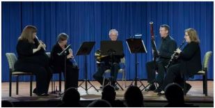 Woodwind ensemble performing on stage.