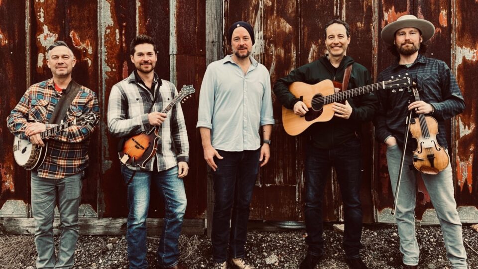 Band posing in front of rusted wall.