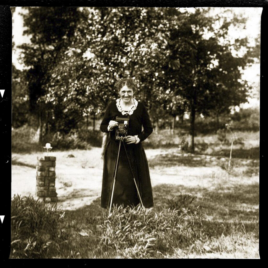 Woman holding a camera outdoors.