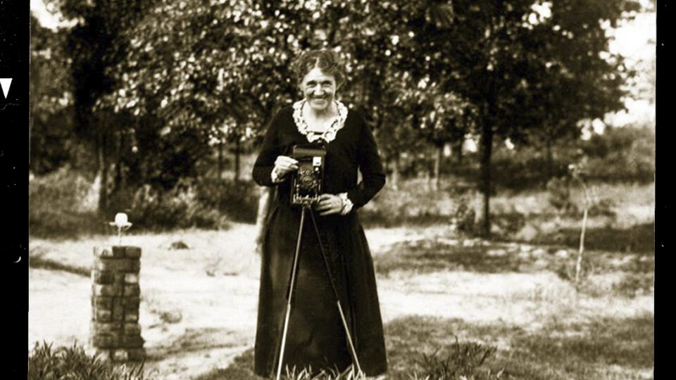 Woman holding a camera outdoors.