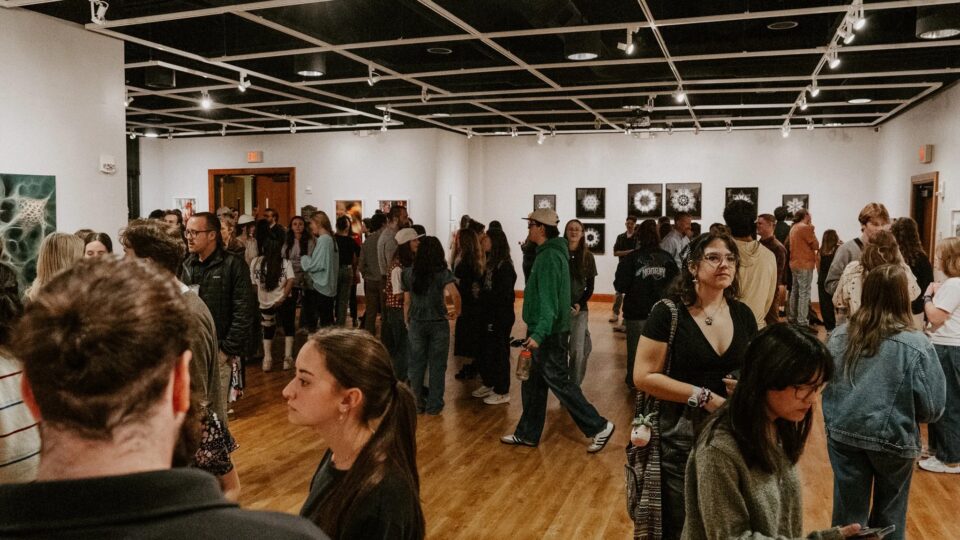 Crowded art gallery event with attendees.