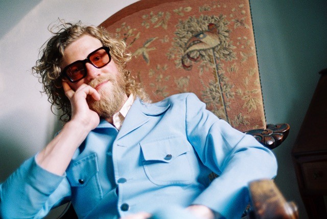 Man in blue suit, sunglasses, smiling