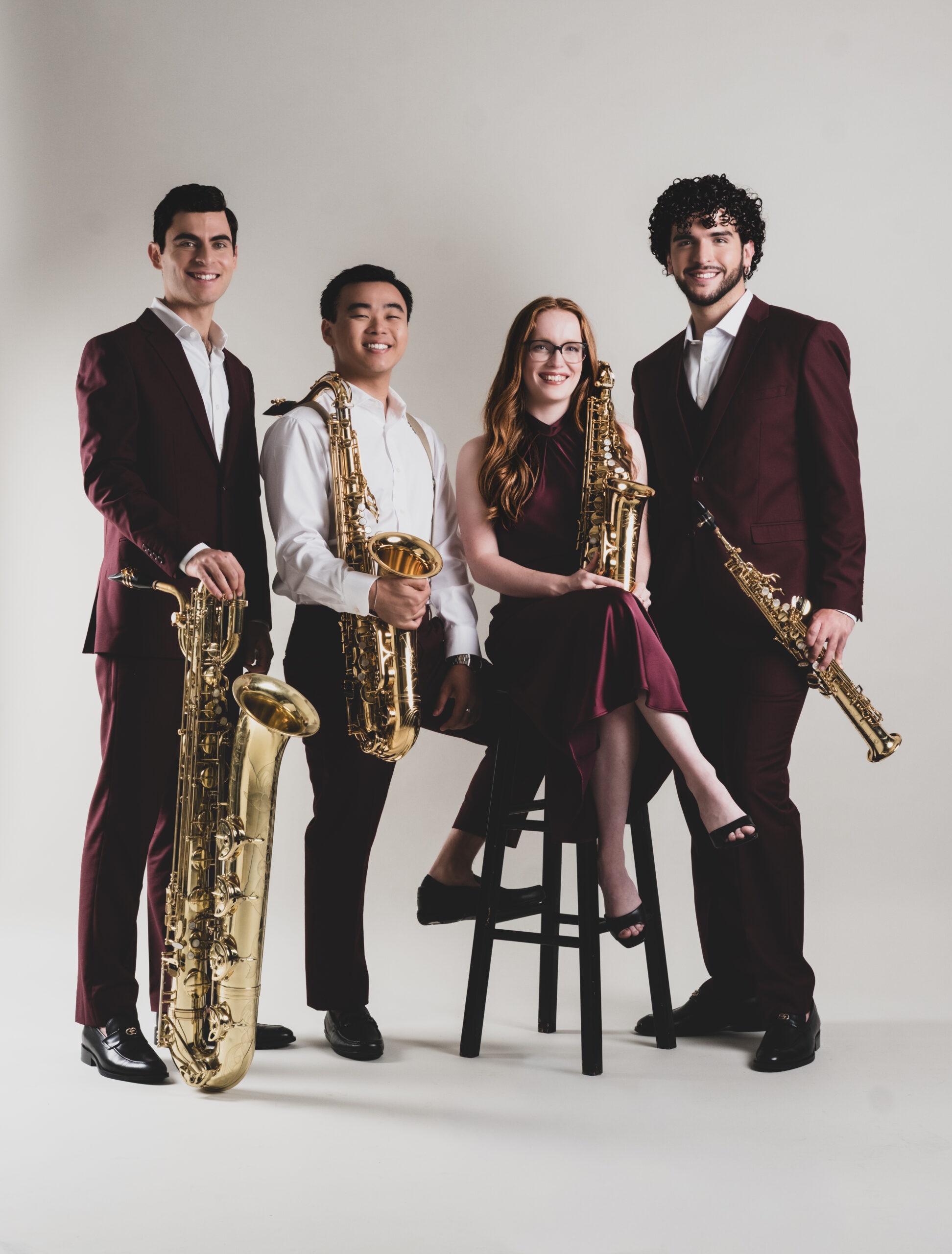 Four musicians with saxophones posing together.