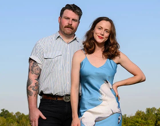 Couple posing outdoors, casual attire.