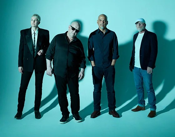 Four musicians posing against backdrop
