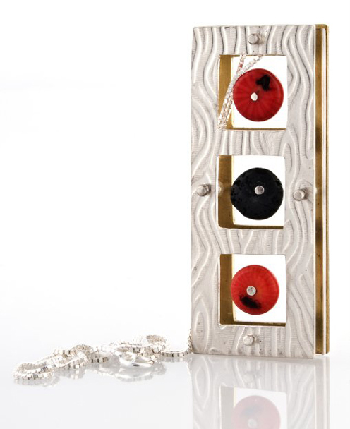 a silver and gold necklace with red and black circles