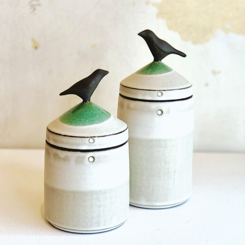 a pair of ceramic jars with a bird on top